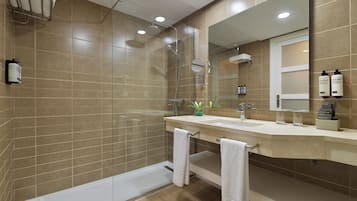A modern bathroom with a glass-enclosed shower, a large mirror, and a vanity with a sink and towel rack.