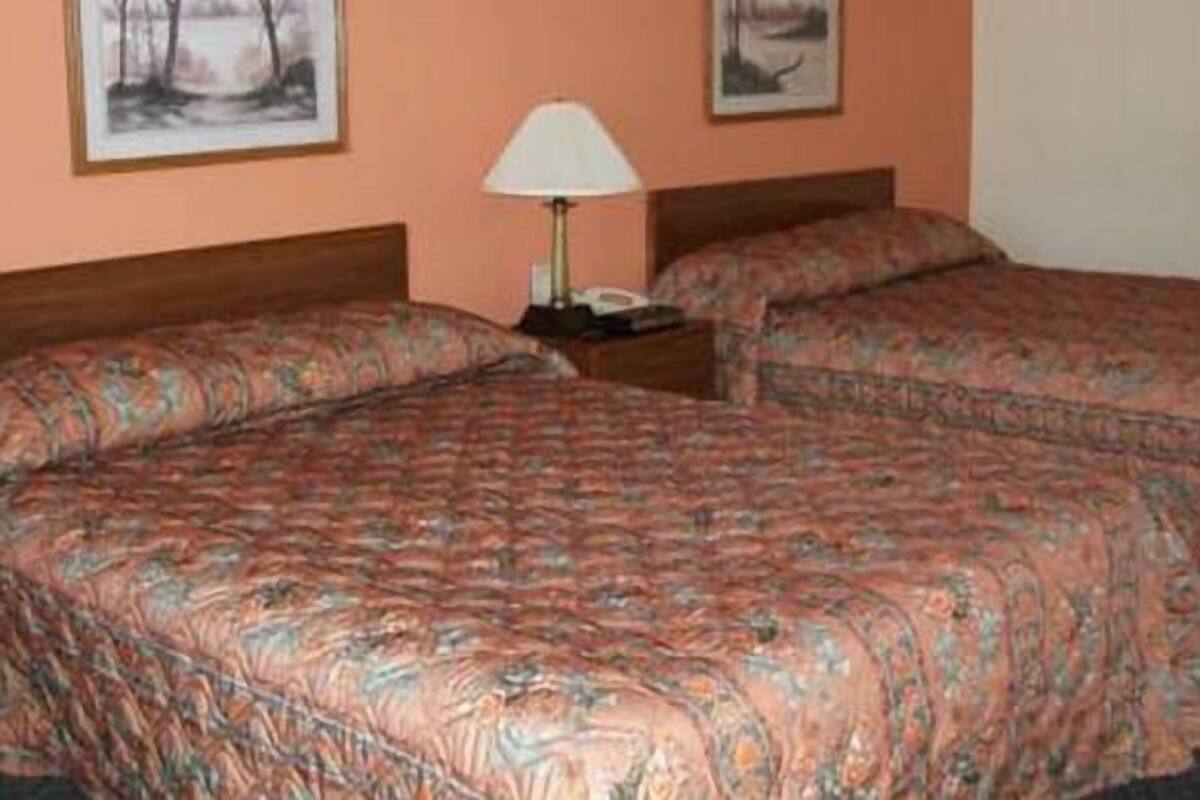 Un dormitorio con dos camas, una mesita de noche y una lámpara.