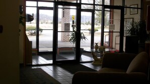 Un vestíbulo de hotel con un amplio ventanal que da al exterior, una recepción, un sofá y una pequeña mesa con adornos.