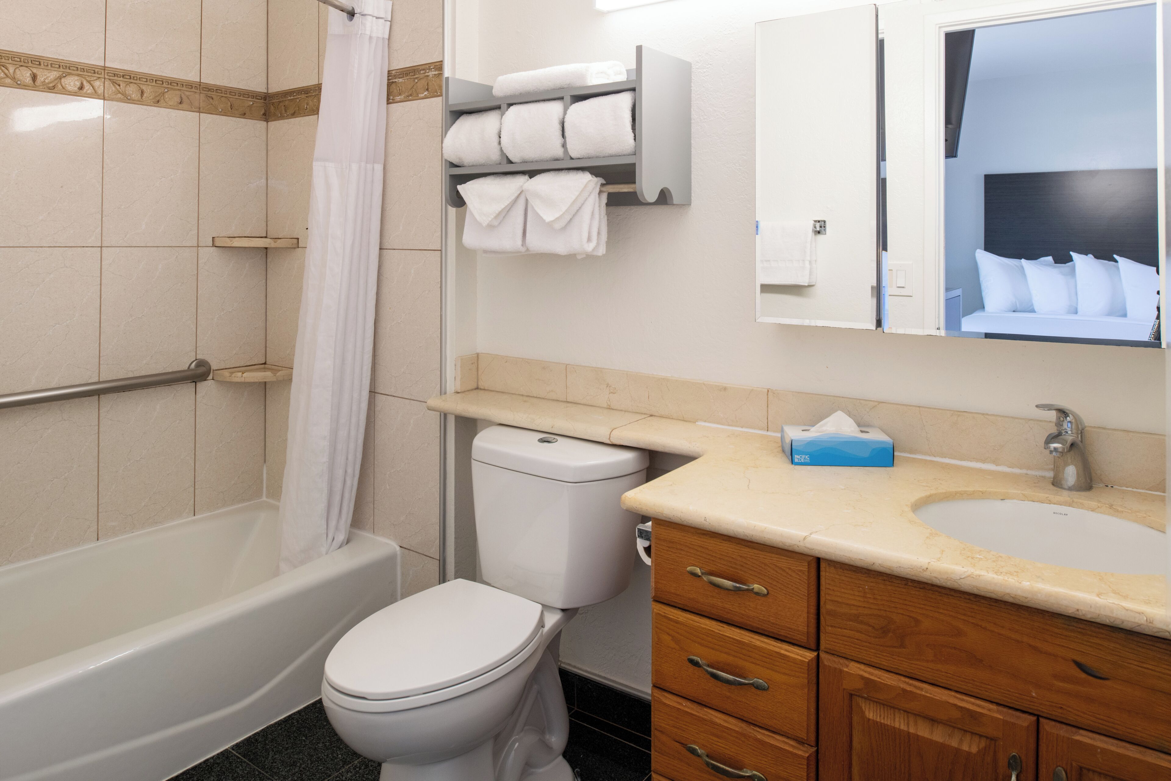 Un baño con bañera, inodoro, tocador con lavabo y espejo.