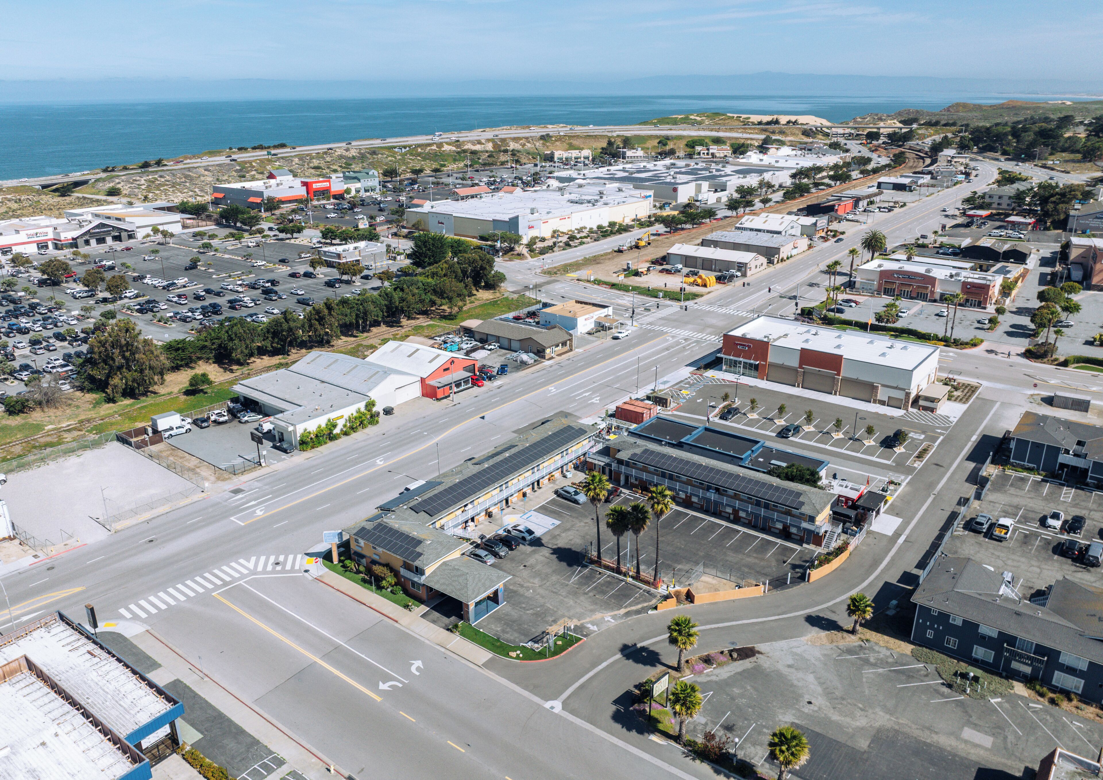 An aerial view of a commercial area with multiple buildings, roads, and parking lots.