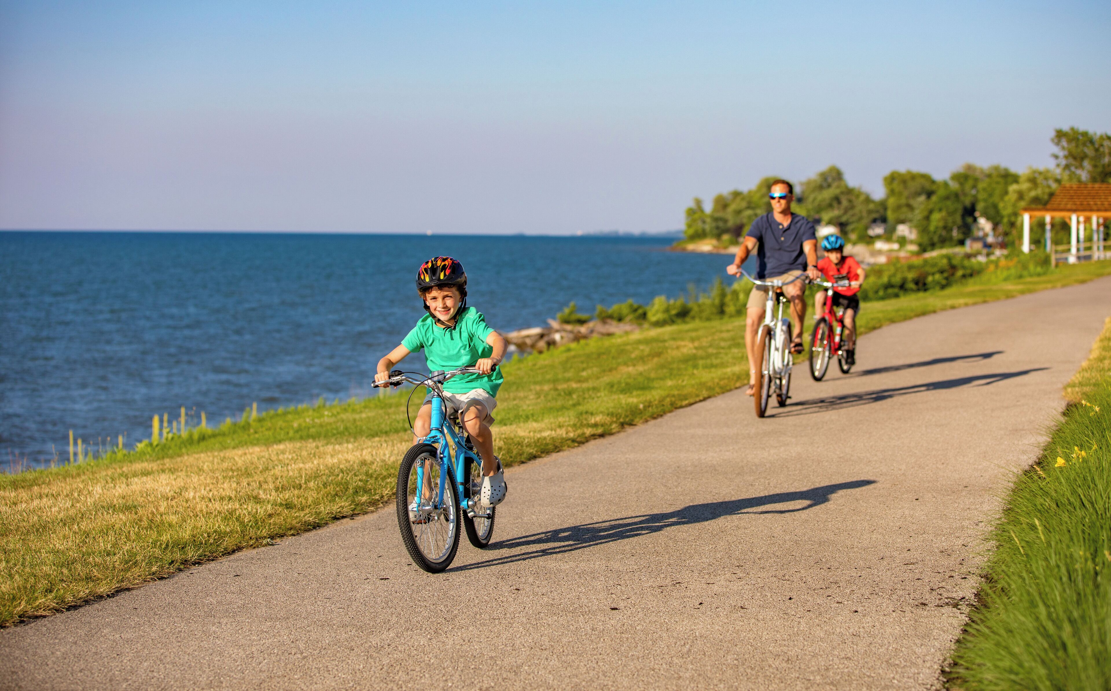 A paved path by the water with cyclists.