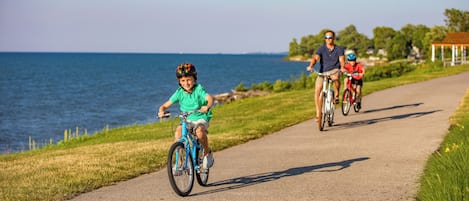 A paved path by the water with cyclists.