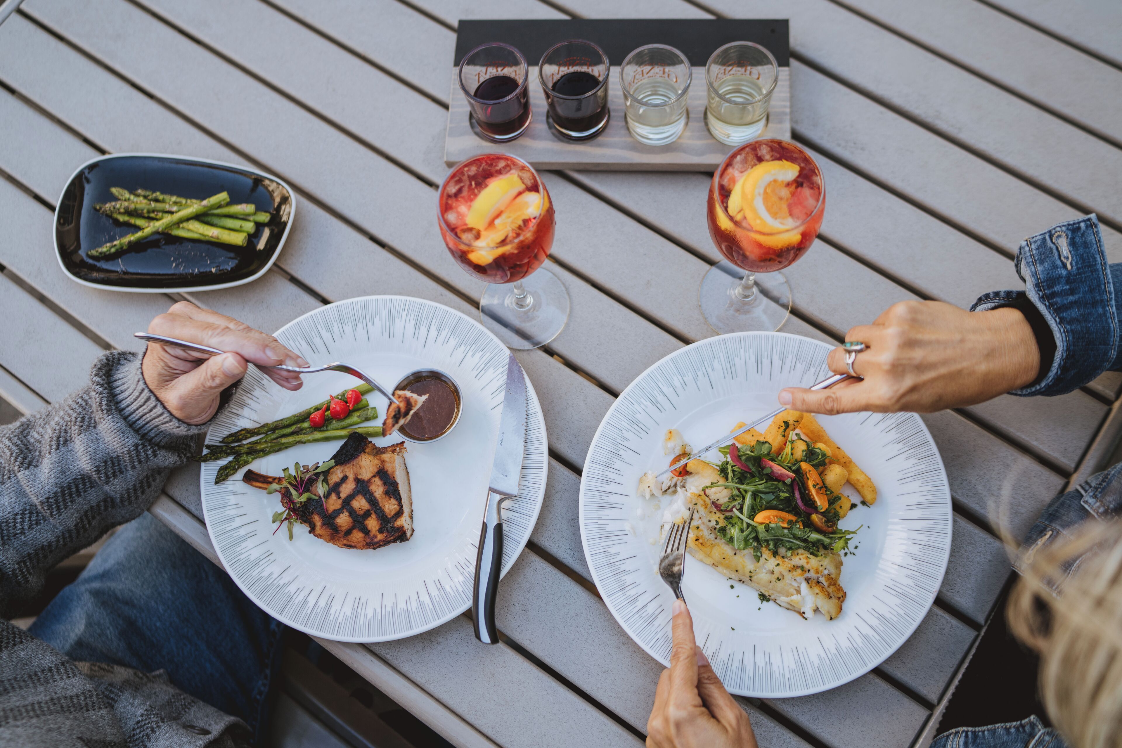 Una mesa de comedor con platos de comida, cubiertos y vasos con bebidas.