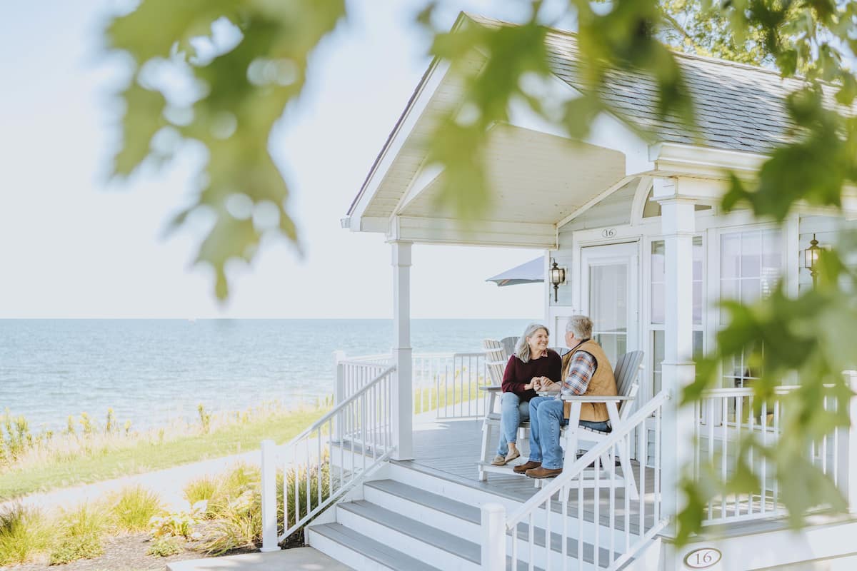 A white wooden porch with a railing, overlooking a body of water.