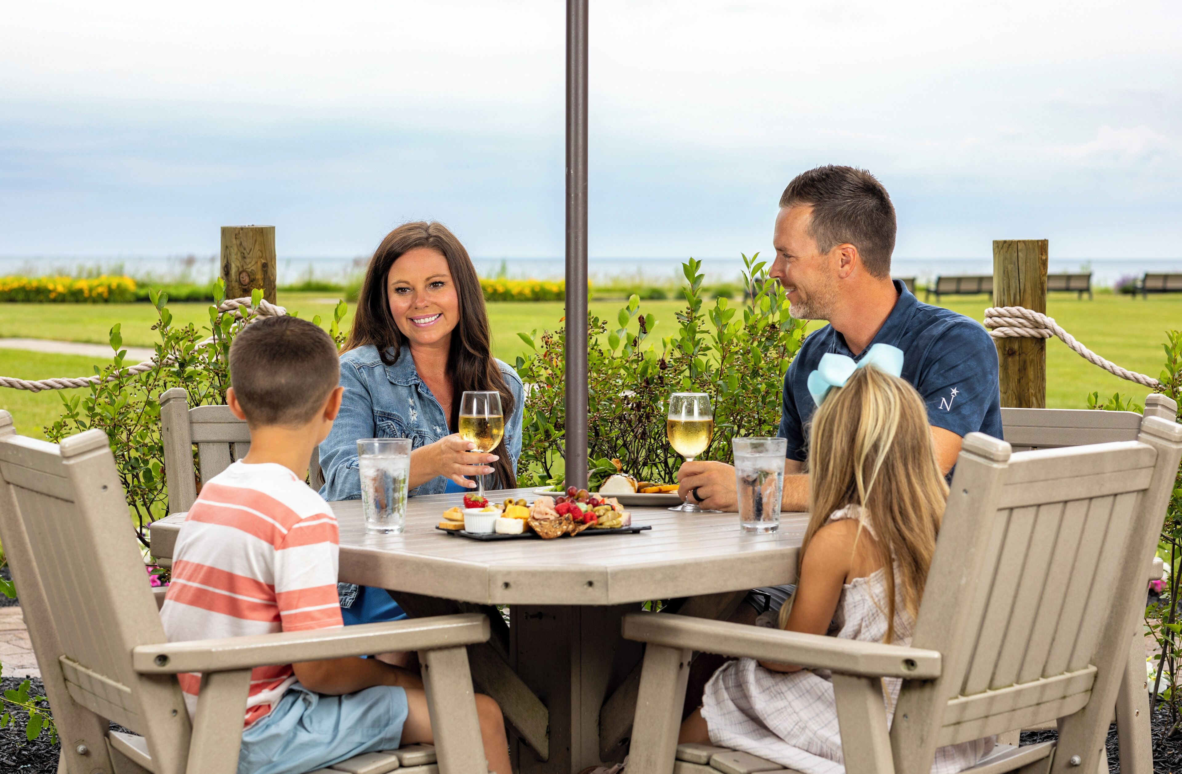 Una familia cenando en una mesa al aire libre con vista al mar.