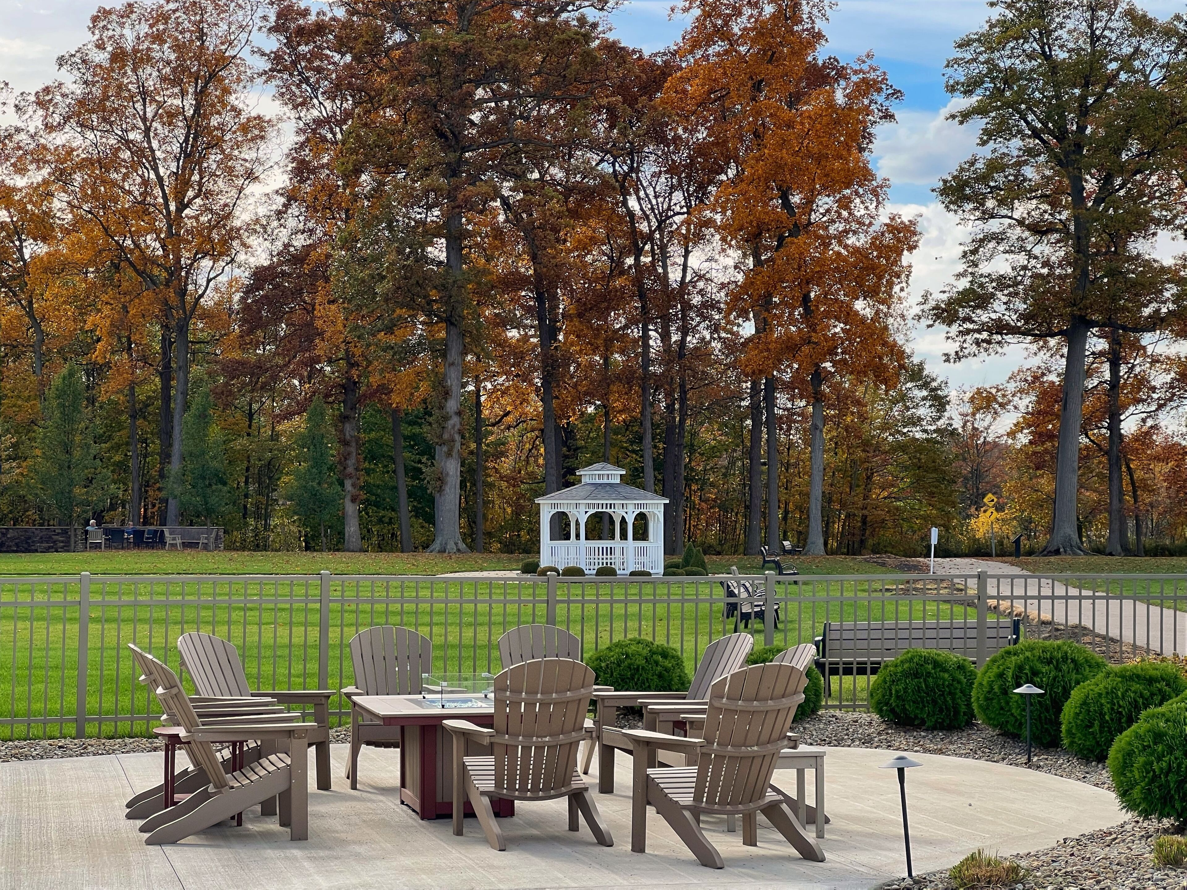An outdoor seating area with Adirondack chairs and a gazebo in the background.