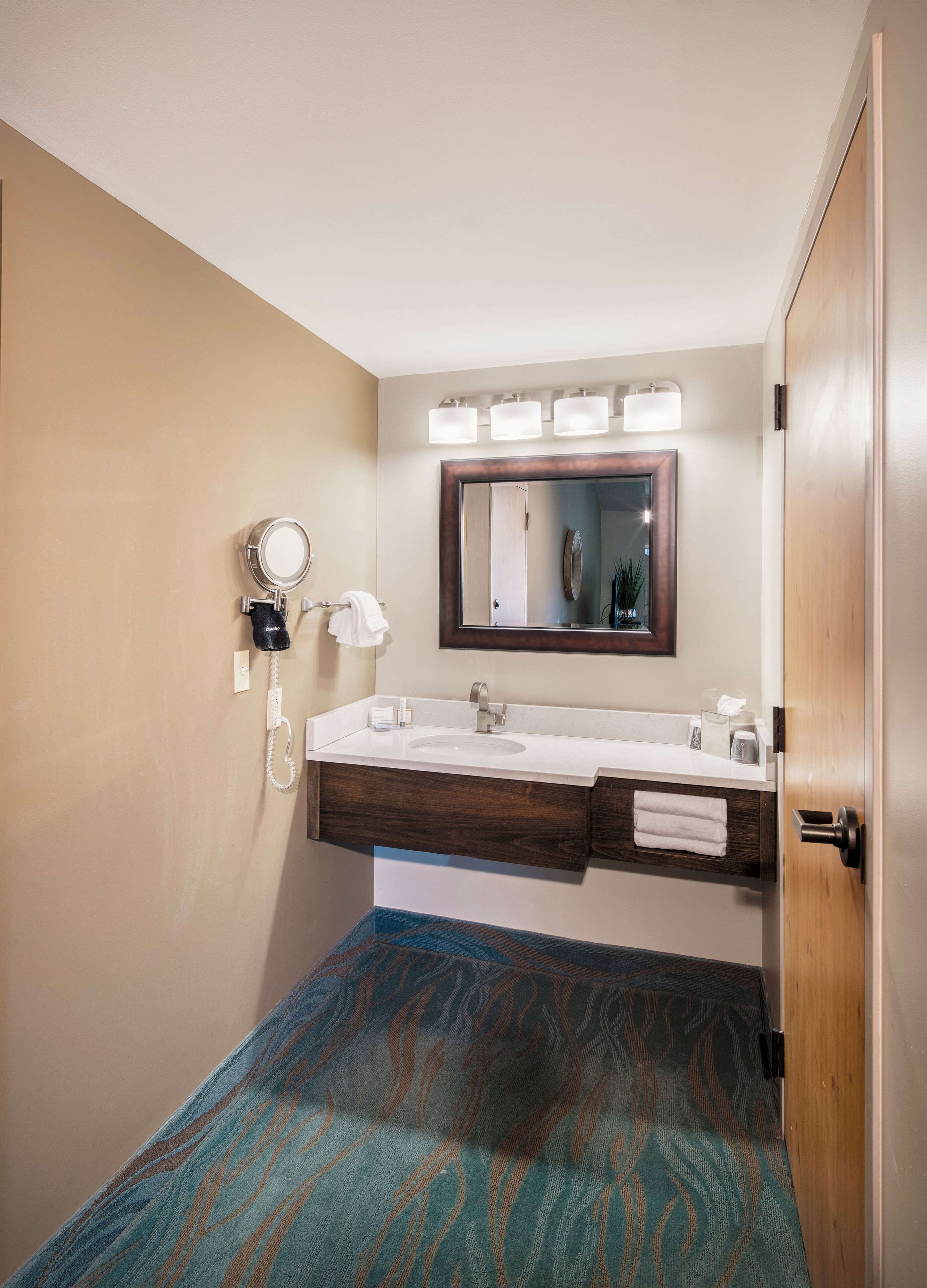 A bathroom with a double sink, a mirror, and a towel rack.