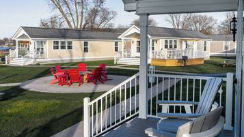 A covered outdoor area with a patio, red chairs, and a white deck.