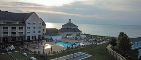 A resort with a pool, tennis courts, and a view of the ocean.