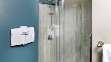 A glass-enclosed shower with a wooden floor, a towel rack, and a light fixture.