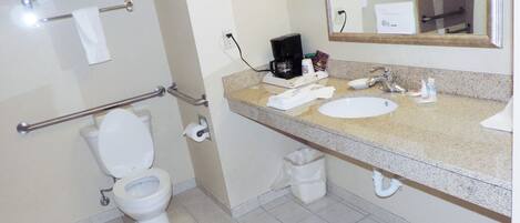 Een badkamer met toilet, wastafel en koffiezetapparaat.