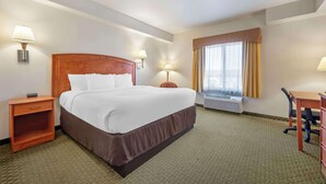 Habitación de hotel con una cama grande, lámparas de noche, un escritorio y un ventanal con cortinas.