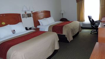 A hotel room with two beds, a desk, a chair, and a window with curtains.