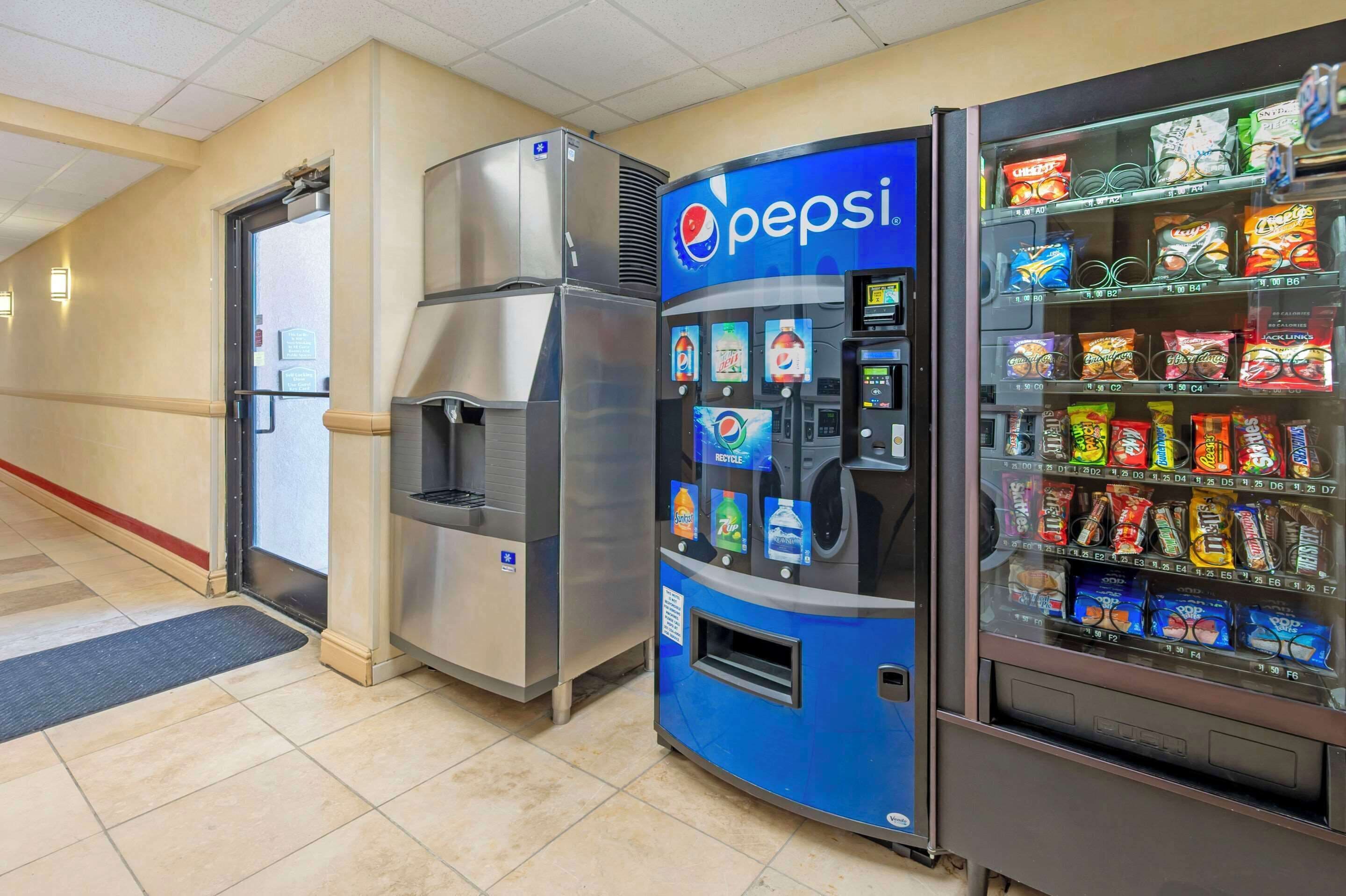 A vending machine with a Pepsi logo, a refrigerator, and a snack vending machine.