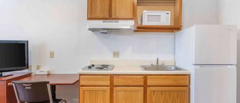 Una cocina compacta con armarios de madera, un microondas, una estufa, un lavaplatos y un refrigerador.