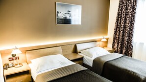 A hotel room with two beds, a nightstand with a lamp, a drawer, and a wall-mounted picture.