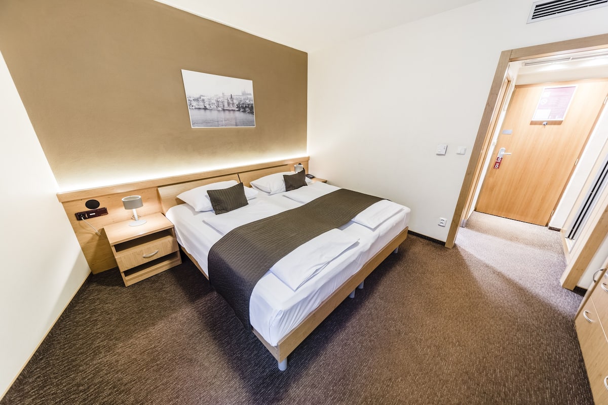 A neatly arranged hotel room with a bed, bedside table, and a wall-mounted picture.