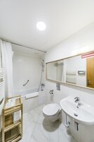 Uma casa de banho moderna com banheira, sanita e lavatório.