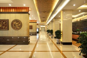 A hotel lobby with a marble floor, a reception desk, and potted plants. - Guilin Lijiang Waterfall Hotel (Guilin)