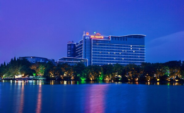 A modern hotel with a prominent building and a body of water in the foreground. - Guilin Lijiang Waterfall Hotel (Guilin)