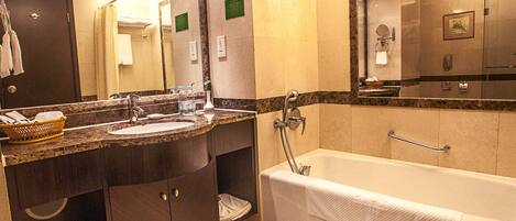 Un baño moderno con un espejo grande, una bañera, un lavabo y un mueble de tocador con una cesta de toallas.