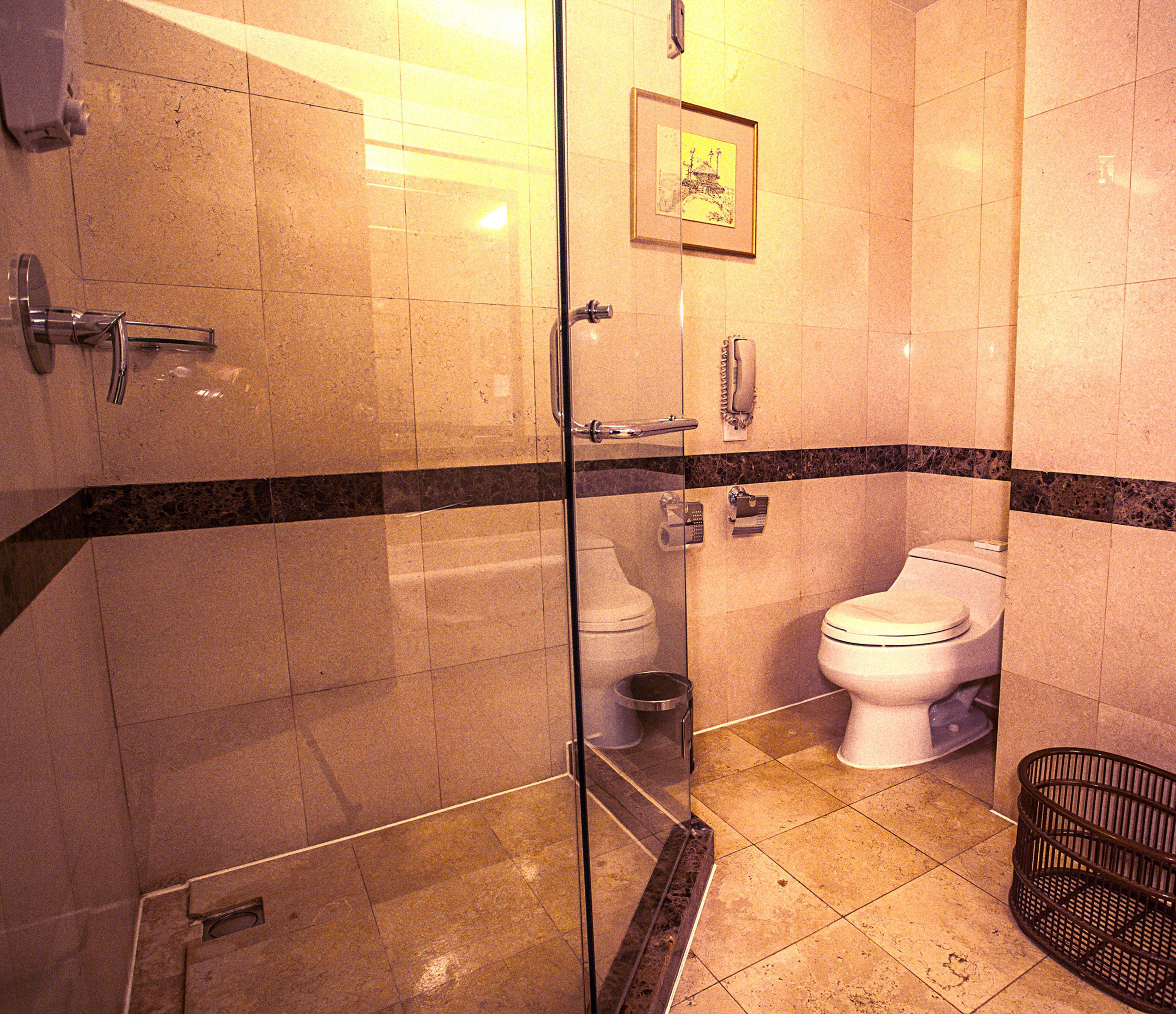 Ein Badezimmer mit Glasdusche, Toilette und Mülleimer.