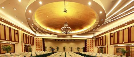 A banquet hall with rows of tables, chairs, and a chandelier.