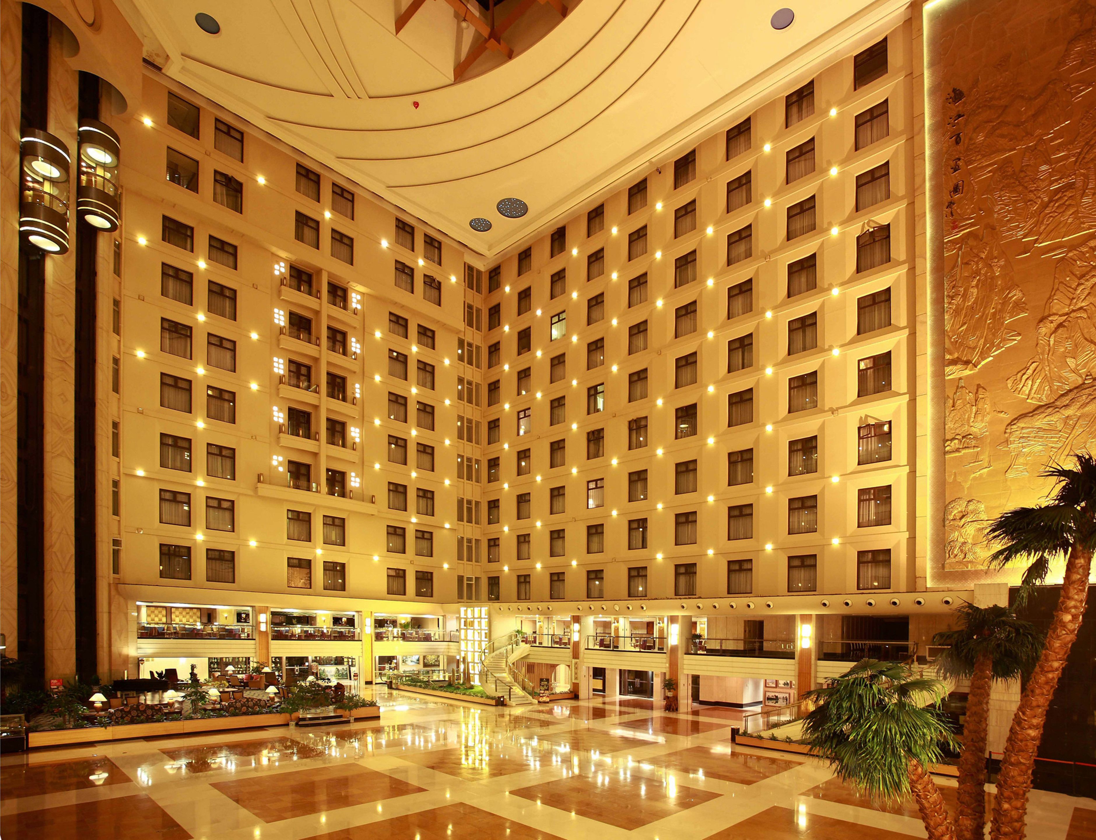 A hotel lobby with a central atrium, multiple floors, and a grand staircase.
