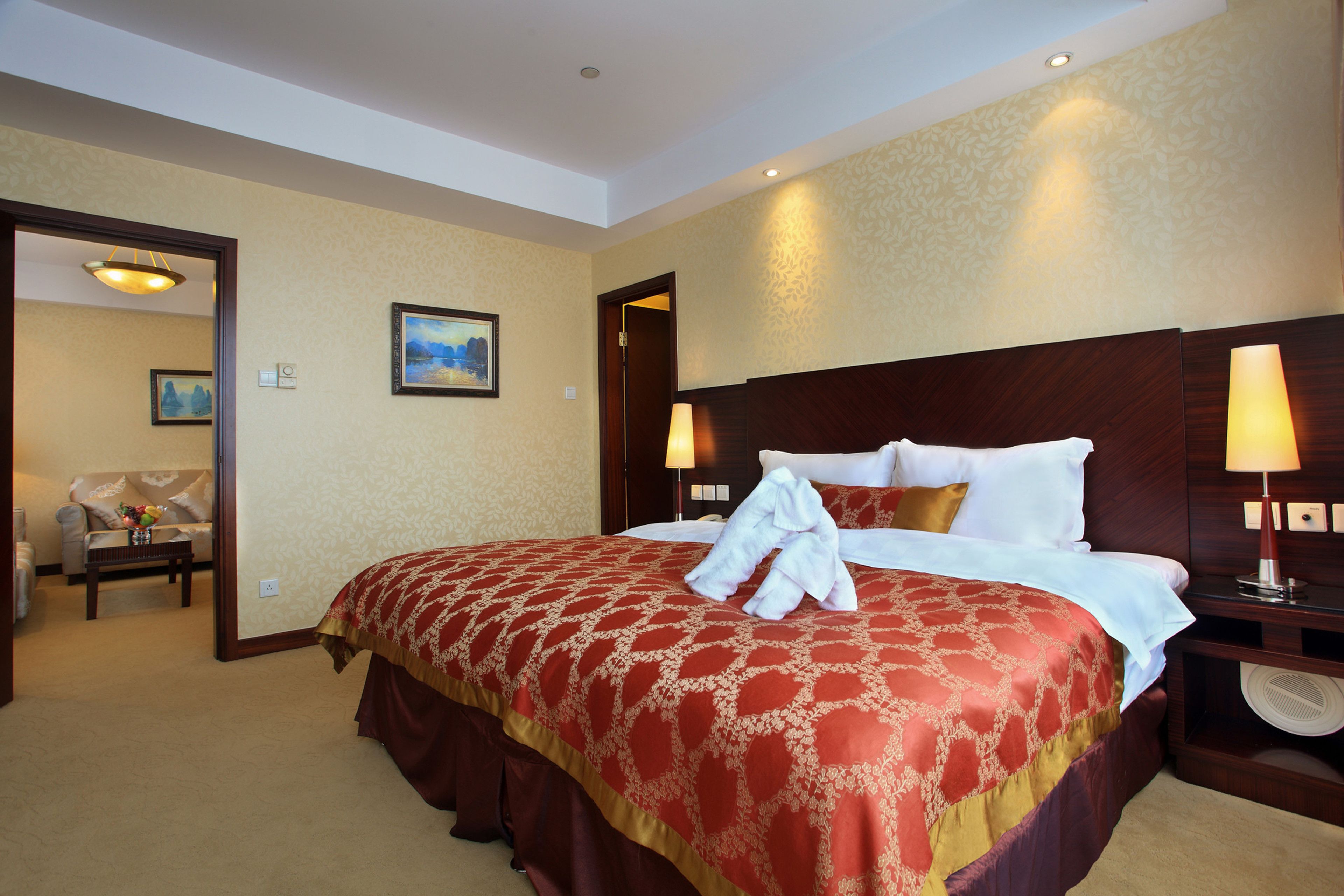 A hotel room with a large bed, two bedside lamps, a nightstand, and a painting on the wall.