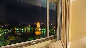 Enjoy a serene view of the city from this room, overlooking a tranquil body of water and a beautifully lit urban park.