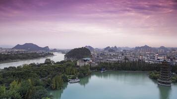 A cityscape with a river, a pagoda, and mountains in the background.