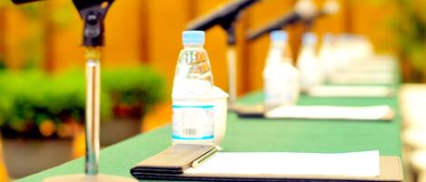 A conference table with microphones, a water bottle, and a notepad.