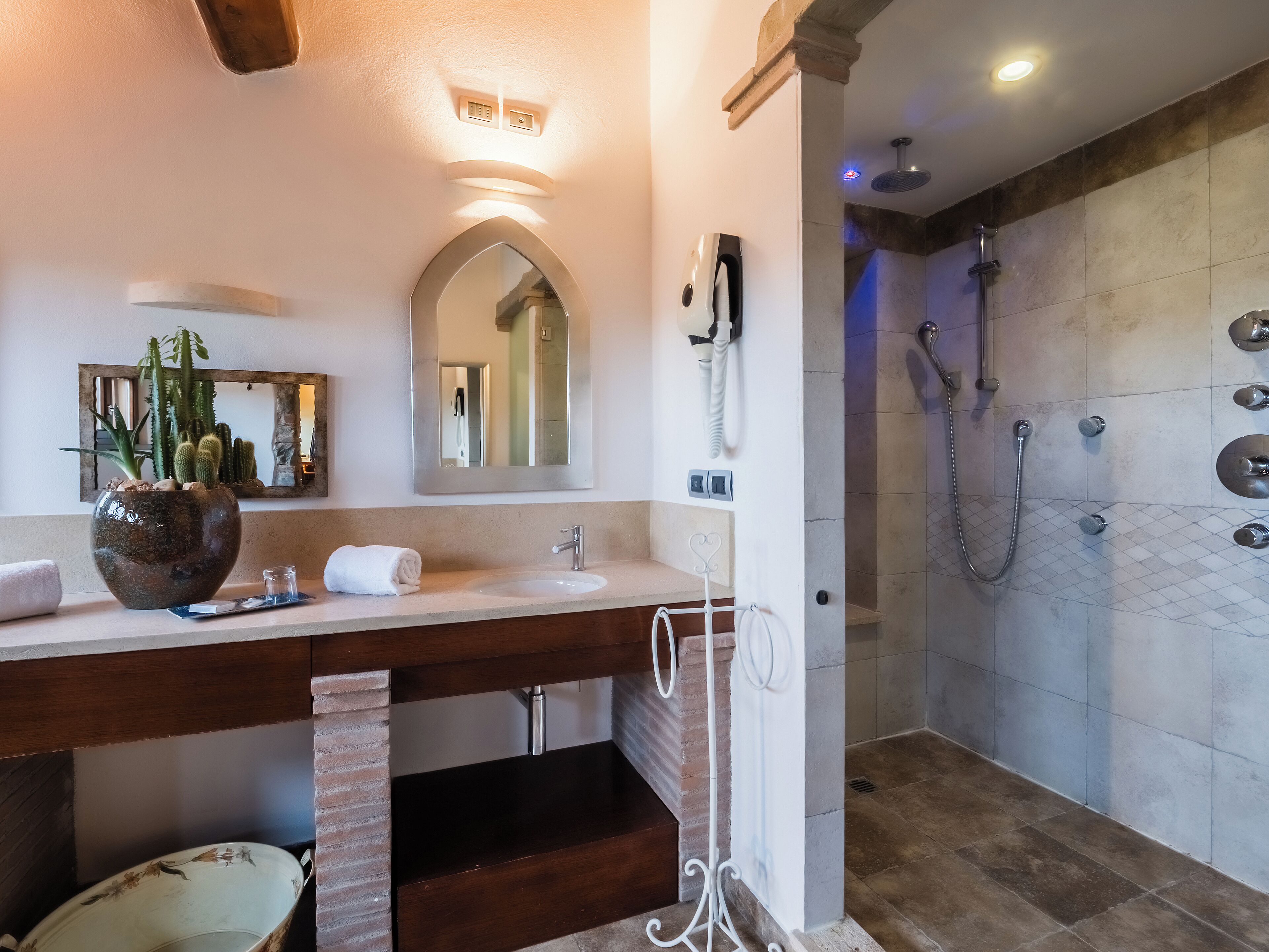 A bathroom with a sink, mirror, and shower.