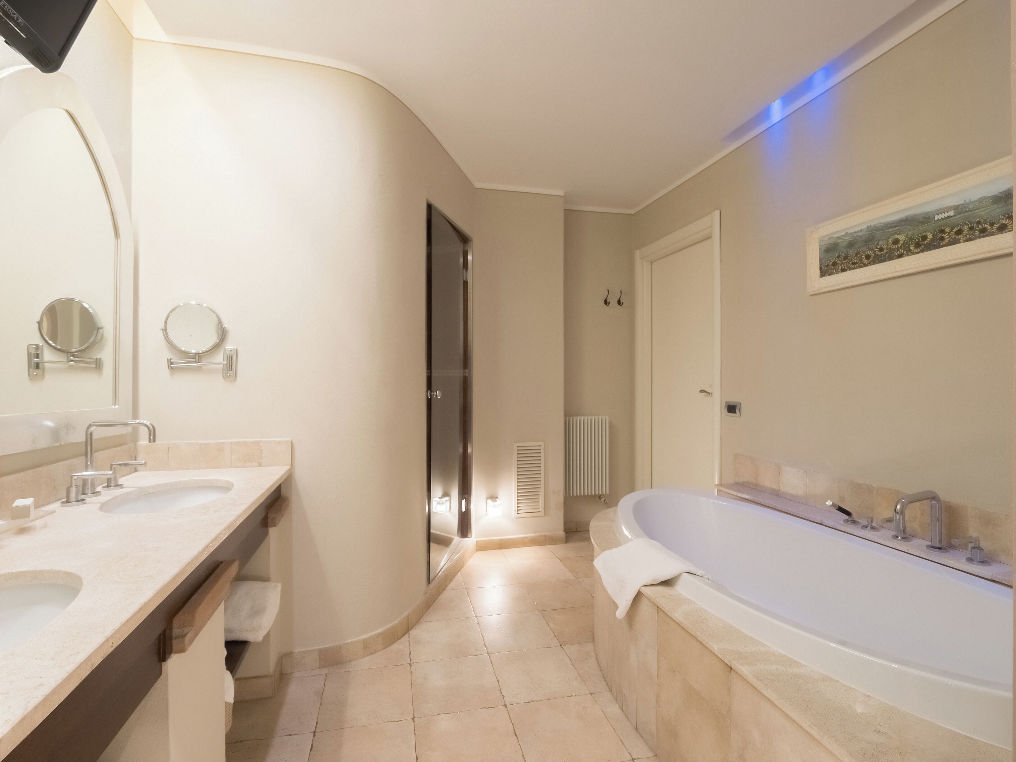 Un baño moderno con dos lavamanos, una bañera grande y un espejo.