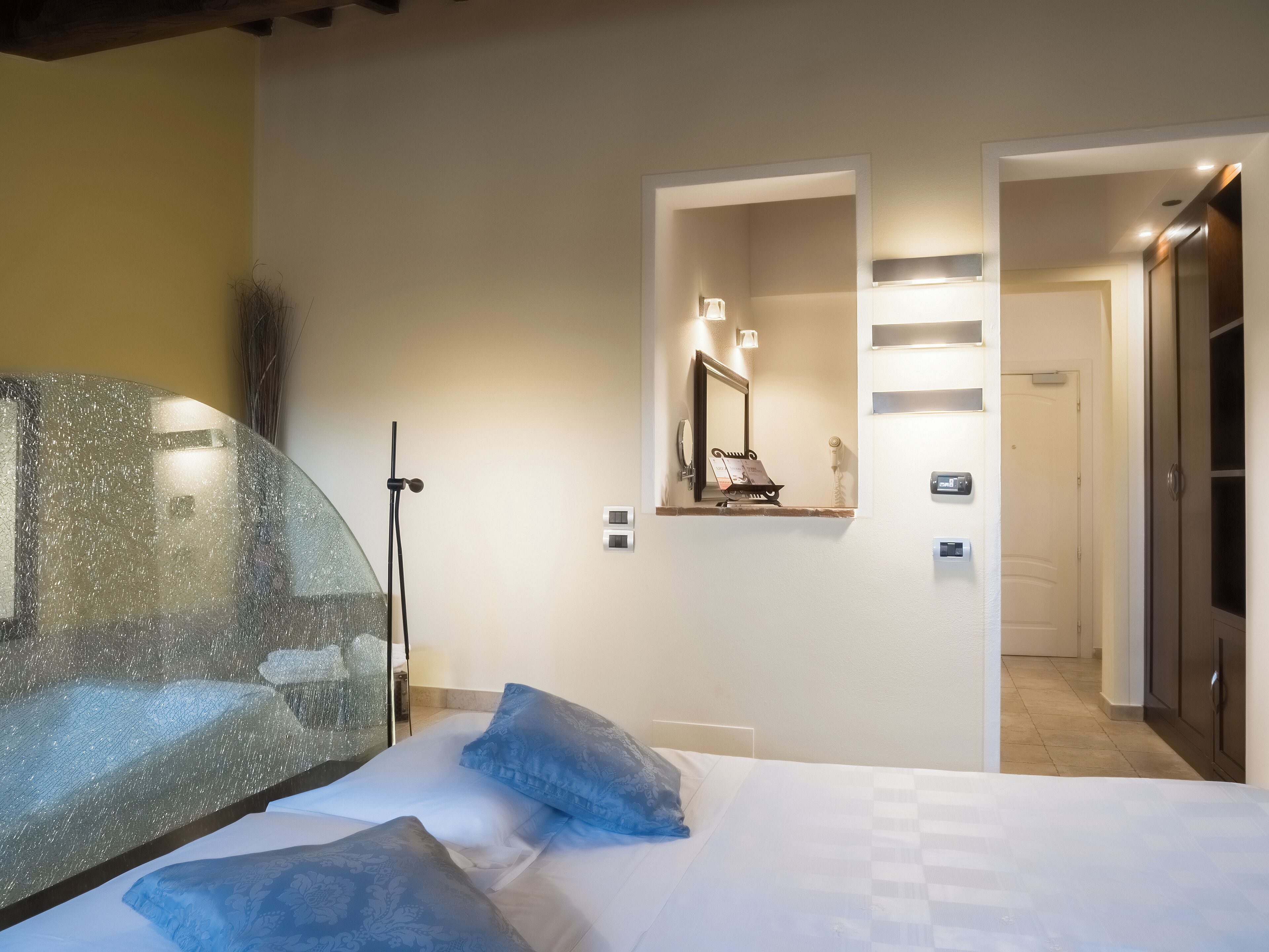 A bedroom with a bed, pillows, a mirror, and a shower area.