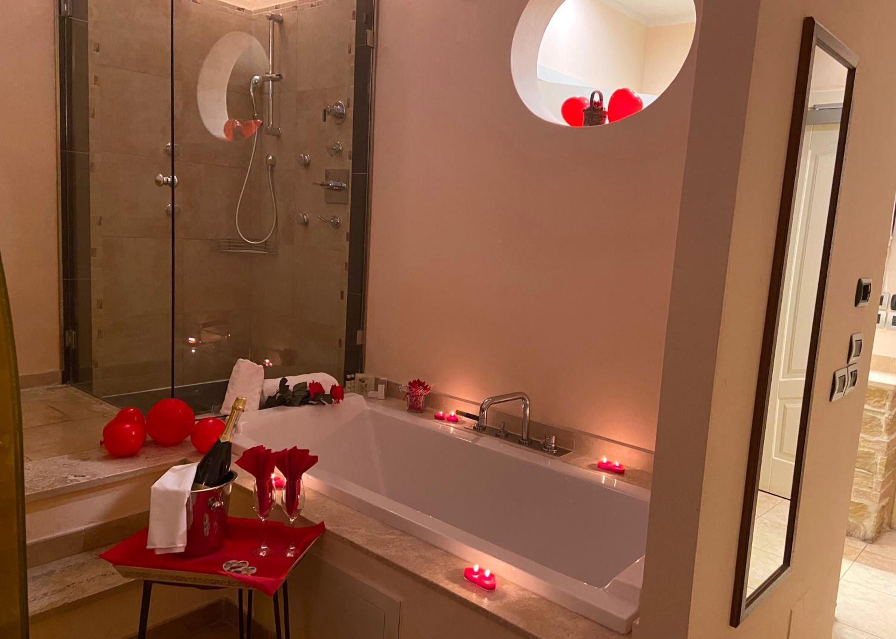 Ein modernes Badezimmer mit einer großen Badewanne, einer Dusche und einem runden Spiegel.