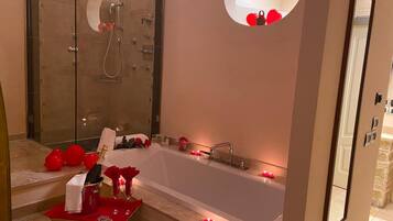 Ein modernes Badezimmer mit einer großen Badewanne, einer Dusche und einem runden Spiegel.