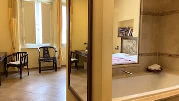 A hotel room with a large bed, a bathtub, and two wooden chairs.