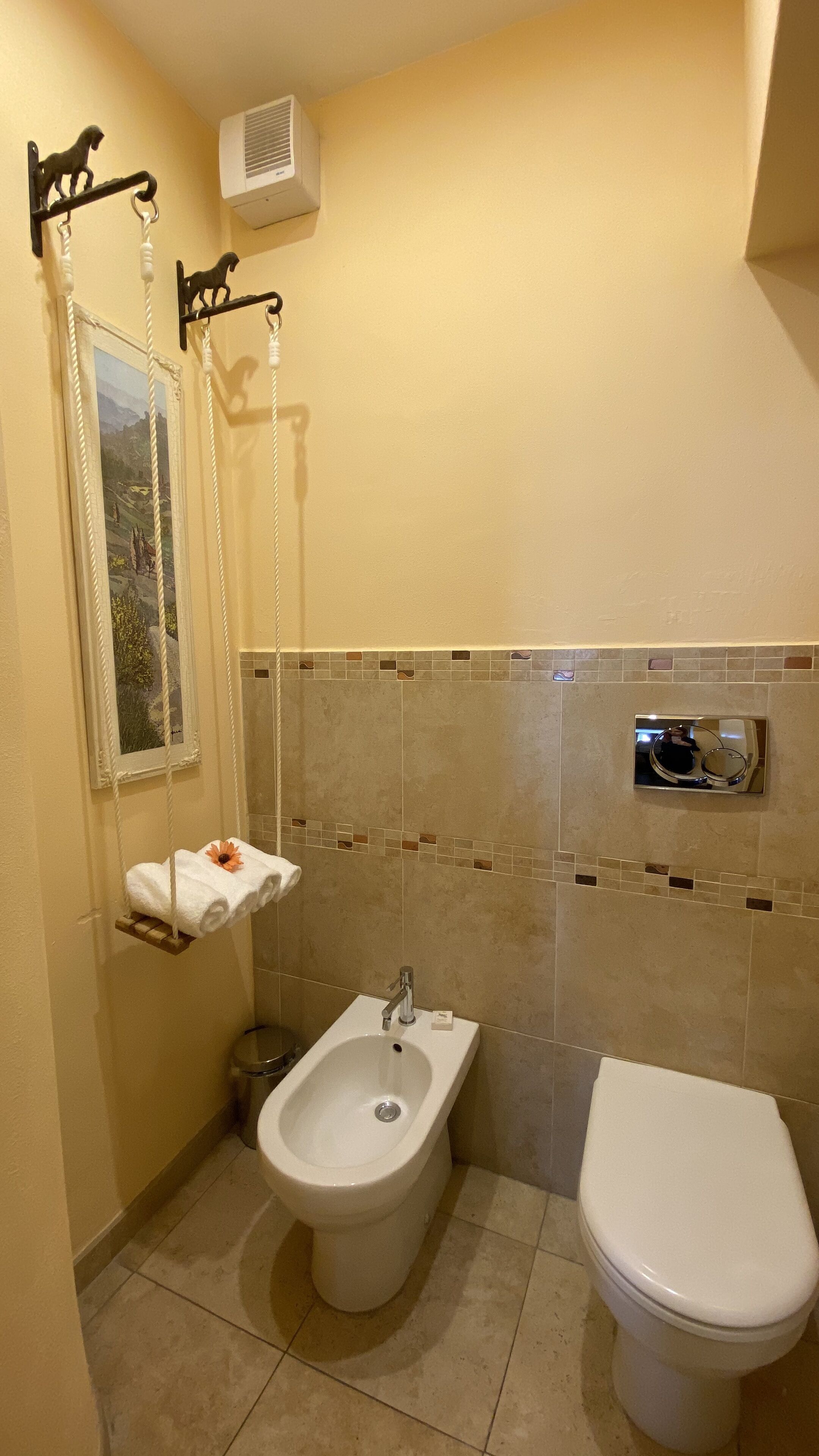 A bathroom with a bidet, toilet, and a towel rack with a towel.