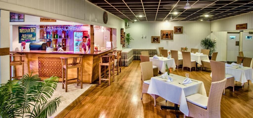 A restaurant with a bar area, multiple tables, and chairs.