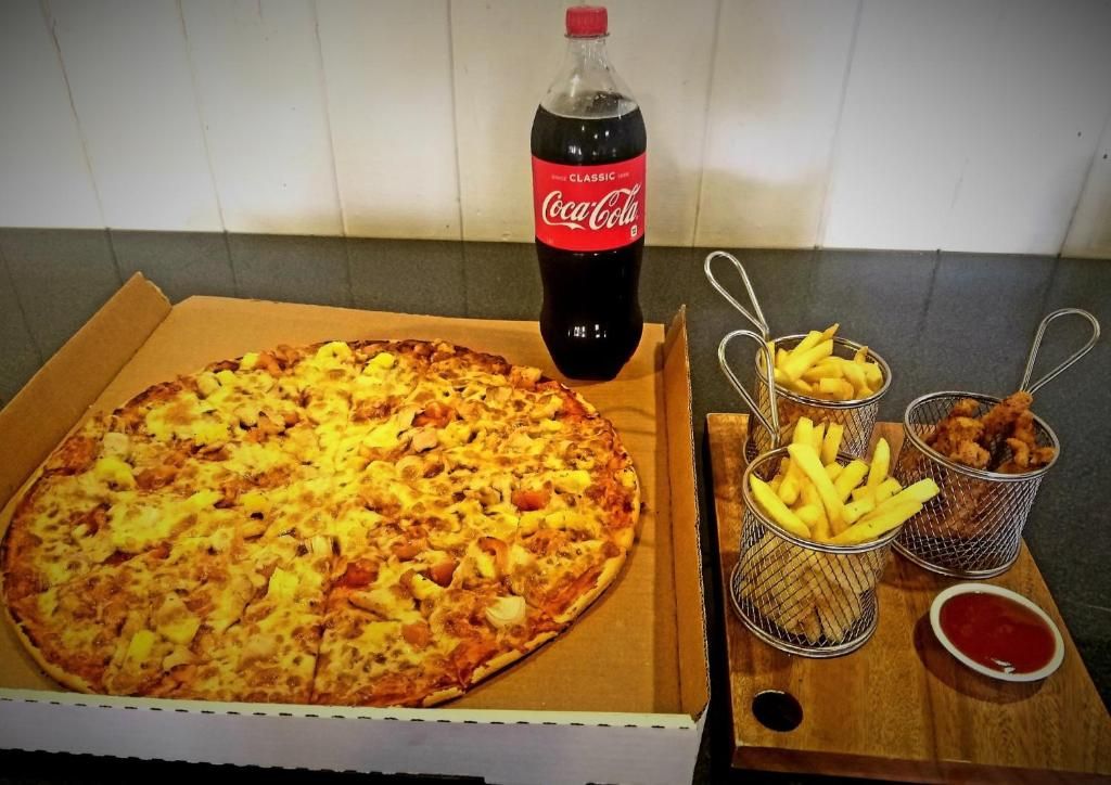 Una caja de pizza con una pizza grande, una botella de Coca-Cola y dos cestas con papas fritas y tiras de pollo.
