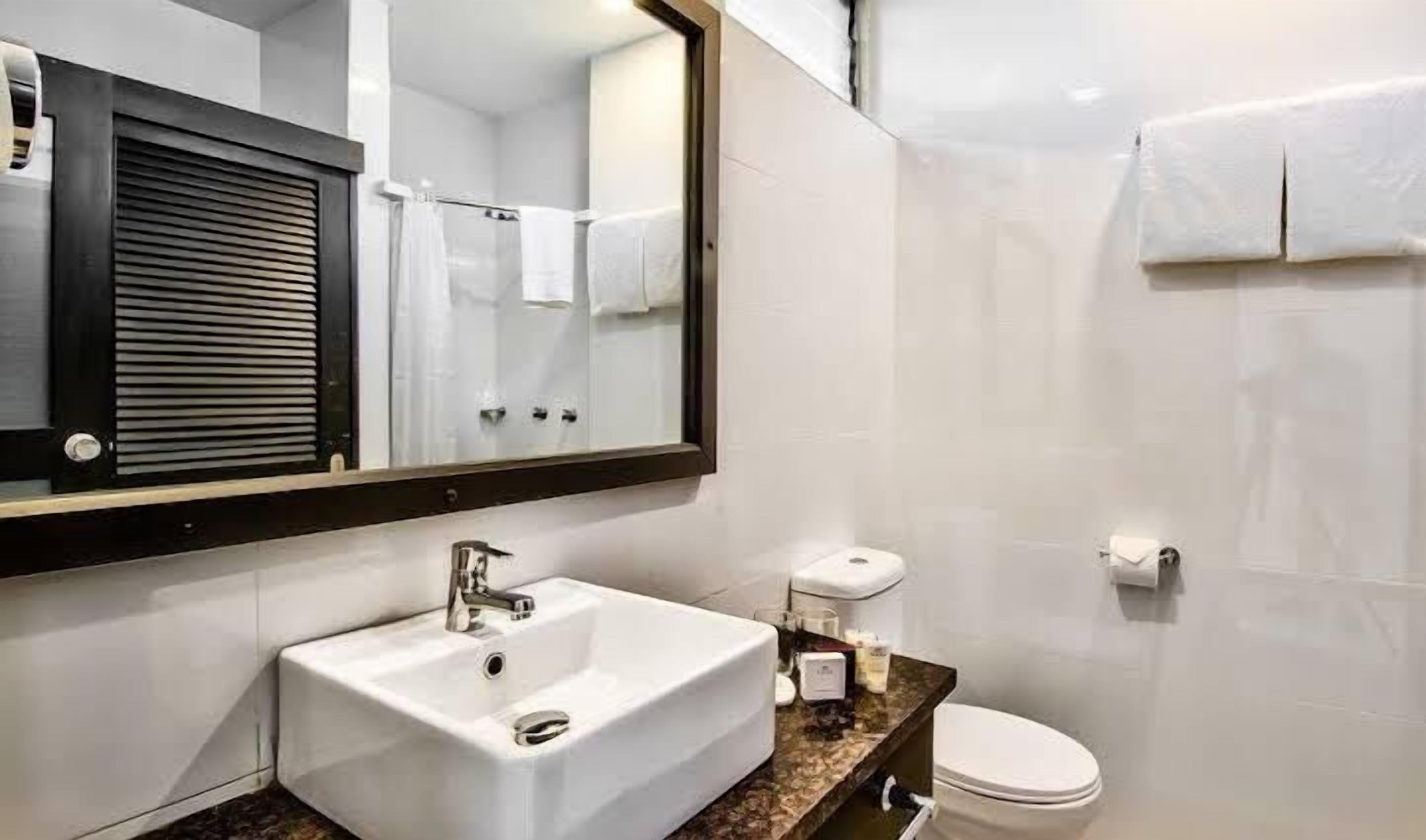 Un baño con lavamanos, inodoro y espejo.