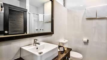 Un baño con lavamanos, inodoro y espejo.
