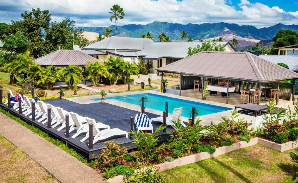 A resort with a swimming pool, lounge chairs, and a view of mountains.