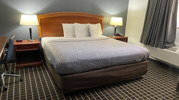 A hotel room with a large bed, two bedside tables with lamps, a desk, and a chair.