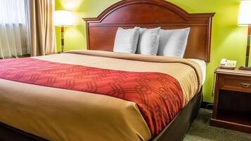 A hotel room with a large bed, a wooden headboard, two bedside lamps, and a painting on the wall.