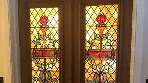 A wooden door with stained glass panels featuring floral designs. - Jackson House B&B (Railroad)