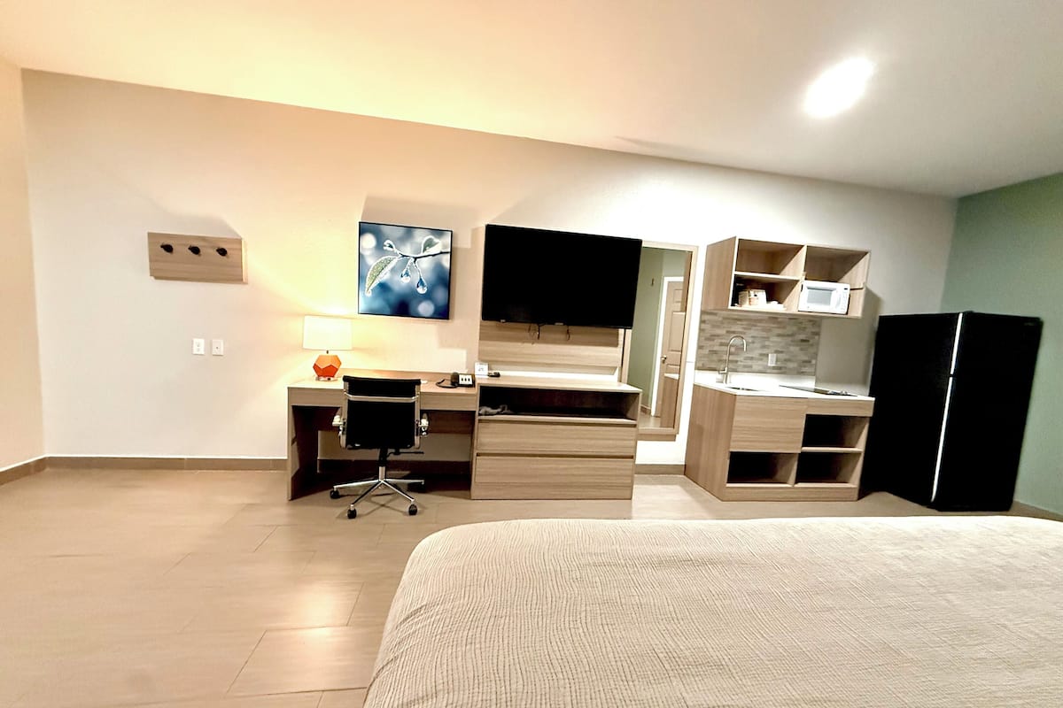 Une chambre d’hôtel équipée d’un lit, d’un bureau, d’une chaise, d’une télévision, d’un four à micro-ondes et d’un réfrigérateur.