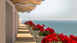 Een balkon met rode bloemen en uitzicht op zee.